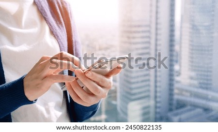 A woman operating a smartphone with the city in the background.