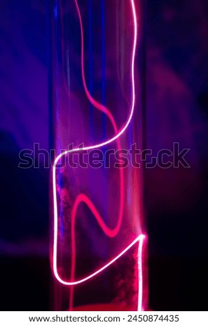 A purple and blue glowing tube with a red line running through it. The tube is lit up and he is a neon light Royalty-Free Stock Photo #2450874435