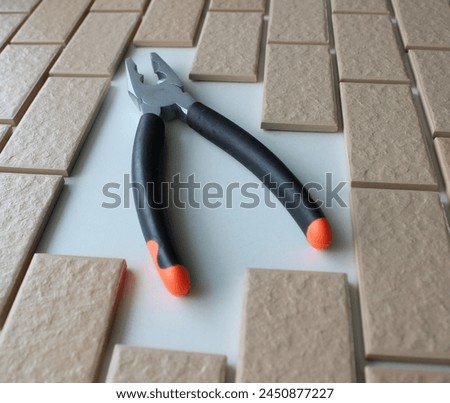 Rubberized Handles Of Pliers On Free Space On A Surface Covered With Brick Tiles. Home Repairing Square Stock Photo 
