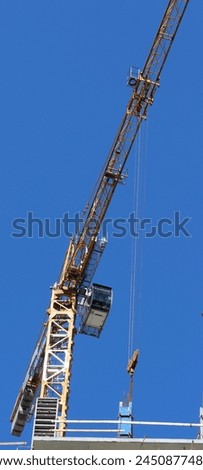 Operator Cabin And Long Boom Of High Rise Construction Crane On Blue Sky Background Vertical Stock Photo
