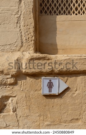 Restroom sign arrow. Ladies Toilet restroom sign on a yellow background wall. Public washroom bathroom wc