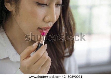 Closeup of young asian woman applying pink lipstick. Concept for beauty, cosmetic, personal grooming, or fashion. Royalty-Free Stock Photo #2450890031