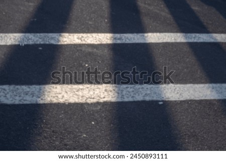 White lines cross the asphalt road as a warning sign for road users