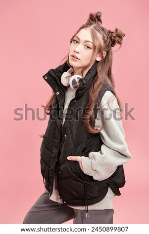 Cute teenage girl, dressed in loose casual clothes, with cute hair bumps on her head and wavy hair. Pink background. Youth style.