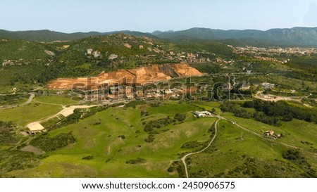 Aerial view of the former Monteponi mine, near Iglesias in Sardinia, Italy. The red color is due to the zinc and lead present in the soil. The mining plant is now closed. Mining concept. Royalty-Free Stock Photo #2450906575