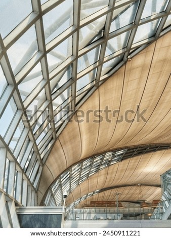 Architectural photography capturing the intricate design of a modern airport terminal's roof with its metallic frame and the play of light and shadows