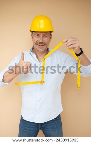 man, architect, technician, builder, polisher with yellow safety helmet and yellow folding rule against a brown background Royalty-Free Stock Photo #2450915935