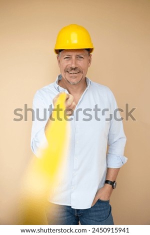 man, architect, technician, builder, polisher with yellow safety helmet and yellow folding rule against a brown background Royalty-Free Stock Photo #2450915941