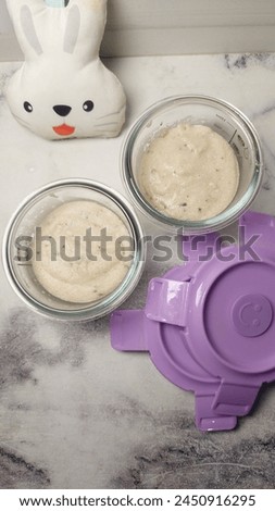 A puree food for baby in the complementary food phase with a soft and mushy texture in two bowls and next to a white rabbit doll.