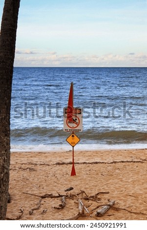 At a Queensland beach, a warning sign depicts a stinger, cautioning swimmers about the presence of dangerous jellyfish in the waters. Royalty-Free Stock Photo #2450921991