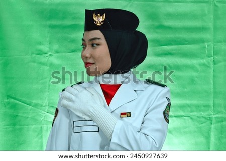 Close up photo young girl Indonesian National Flag Hoisting Troop touching her shoulder. National Paskibraka Council isolated in green background