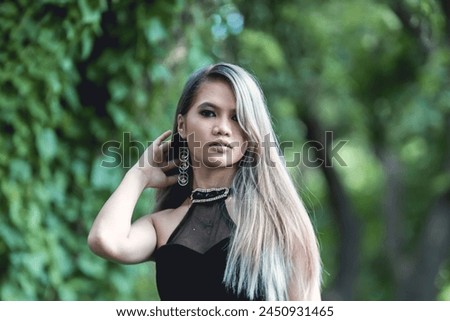 Captivating image of a young woman dressed in gothic-inspired fashion, set against a dense, green forest background. Her expression and attire reflect a blend of modern and mystical themes.