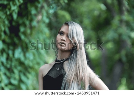 A fashionable young woman dressed in goth-inspired attire stands amidst a verdant forest, conveying a blend of style and nature.