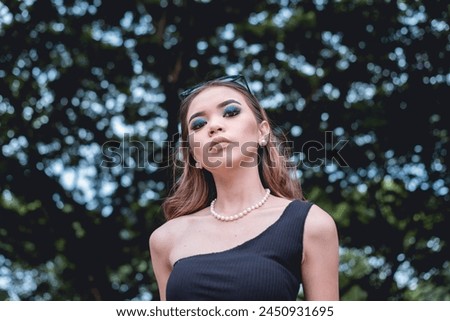 A captivating image of a young woman dressed in goth inspired fashion, standing confidently in a lush forest. Her style contrasts with the natural surroundings, creating a visually striking scene.