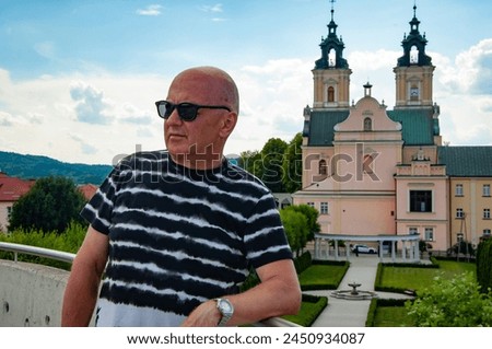 Bold man in summer sunglasses at chapel castle travel destination. Summer castle and man.