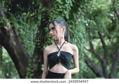 Captivating image featuring a young woman dressed in goth-inspired clothing, surrounded by the natural beauty of a dense, leafy forest.