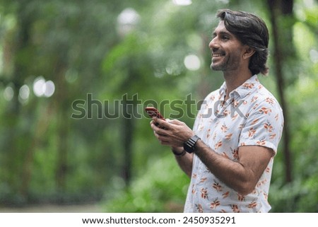 View of a young man with smartphone at daytime in a green park in the city. 
High quality photo. 
