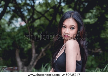 A striking portrait of a young woman dressed in goth-inspired attire, with an enchanting forest as the background, showcasing a blend of style and nature.