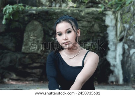 An evocative portrait of a young woman dressed in goth-inspired fashion, set against the ethereal backdrop of an ancient forest.