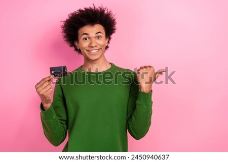 Photo of happy positive guy point finger thumb empty space hold credit card isolated pastel color background