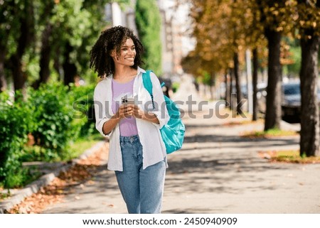 Photo of sweet good mood lady wear white shirt rucksack enjoying journey texting modern gadget outside urban city park