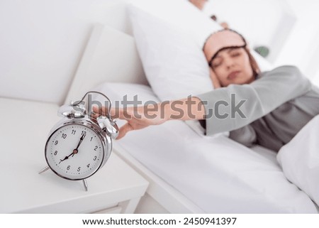 Photo of adorable pretty lady wear grey nightwear lying bed turn ogg ringing clock indoors apartment bedroom