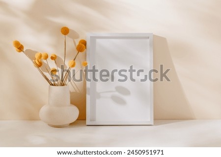Mockup empty photo frame with vase, dry flower bouquet and beautiful sunlight shadows. Wooden photo frame on the table, stylish home interior decoration