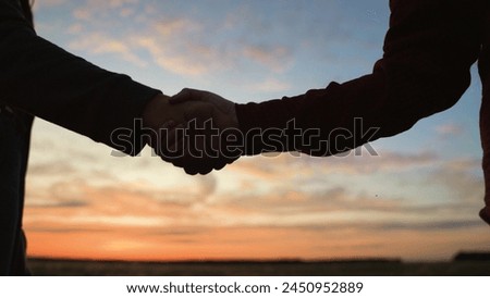 Handshake at sunset, silhouette in park field. Making deal teamwork cooperation successful joint business partnership of two people, farmers greeting saying goodbye showing respect with hand shaking.