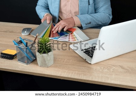  male graphic designer choice color swatch, use laptop, notepad and pen. Interior designer working at office