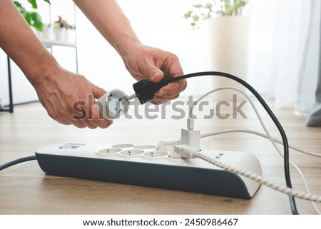 Man plugging the smart power plug. Electrical plug in outlet socket at home.