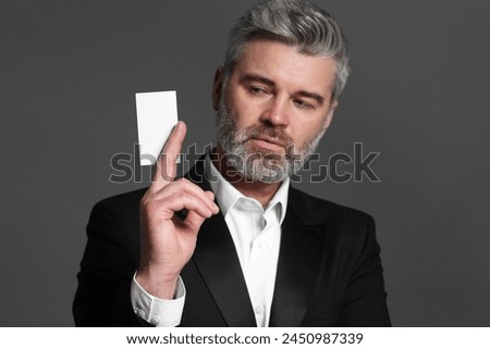 Handsome businessman holding blank business card on grey background