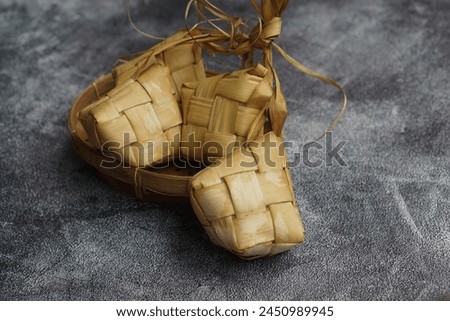 Close up view of Ketupat, an Indonesian traditional cuisine very popular during Hari Raya Idul Fitri served on a wooden table. This is made of the white rice, usually served with opor ayam on Ied day. Royalty-Free Stock Photo #2450989945