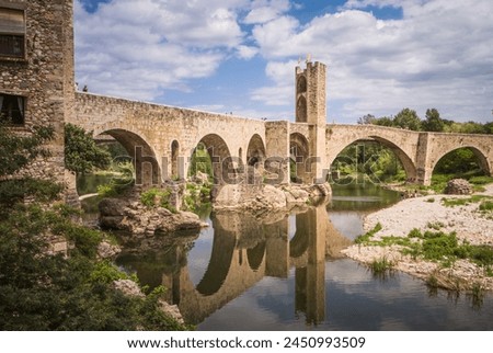 Besalu, Spain, May 12th 2013: Reflections of Besalu: The Ancient Stone Bridge Amidst Nature’s Embrace (Catalonia, Spain) Royalty-Free Stock Photo #2450993509