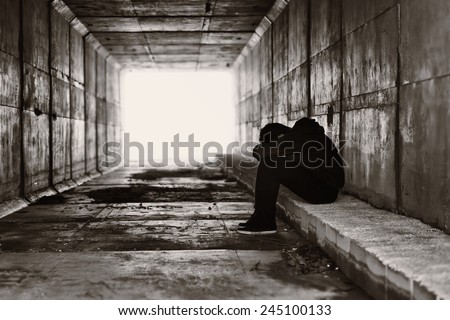 A lonely boy sits on a curb on the right side of a tunnel Royalty-Free Stock Photo #245100133