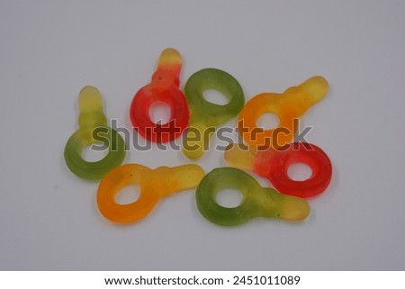 Unusual and non-standard colored jelly green, yellow, red, yellow, orange candies in the form of a key arranged on a white plastic background. Royalty-Free Stock Photo #2451011089