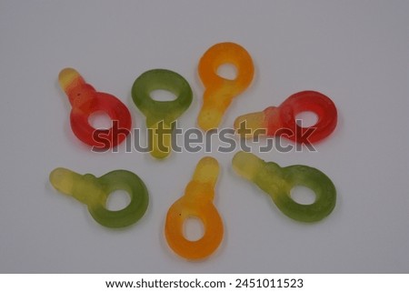Unusual and non-standard colored jelly green, yellow, red, yellow, orange candies in the form of a key arranged on a white plastic background. Royalty-Free Stock Photo #2451011523