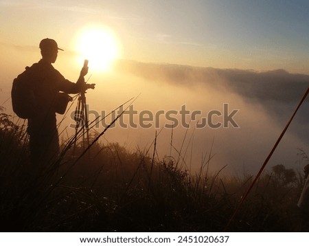 a photographer is photographing a sunrise with a silhouette theme