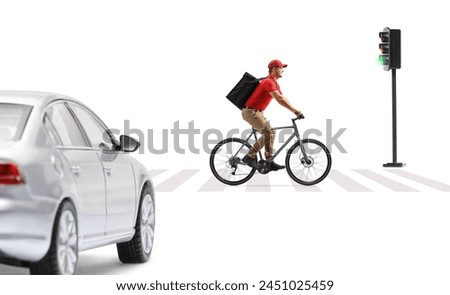 Delivery guy in a red t-shirt delivering food with a bicycle, crossing a road at a pedestrian zebra sign isolated on white background