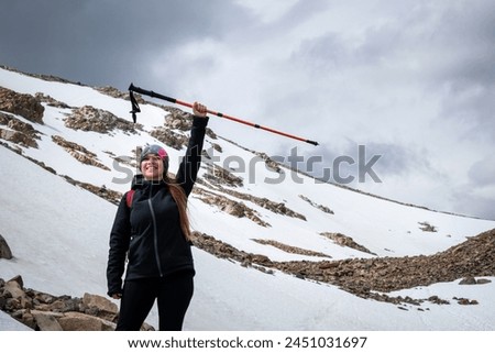Young climber reaching his goal. Young climber happy to have reached Fitz Roy in Argentina. Happy woman managing to reach Fitz Roy. Young female mountaineer with her stick up, conquering adversity Royalty-Free Stock Photo #2451031697