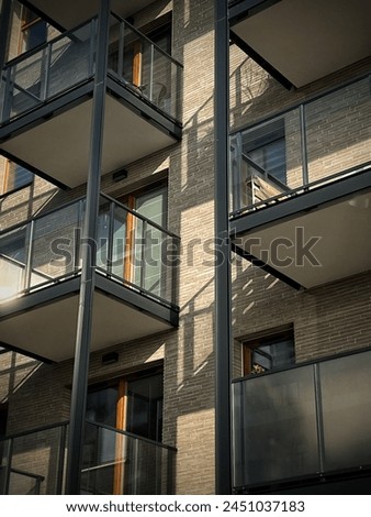 The photo features iron balconies with glass walls, merging modernity with functionality. Against the sky, they stand as contemporary marvels, offering both openness and protection, a harmonious blend