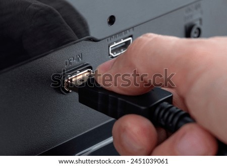 Close-up of a hand plugging a DisplayPort cable into the connector DP-IN. Insert the DisplayPort cable Royalty-Free Stock Photo #2451039061