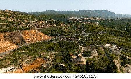 Aerial view of the former Monteponi mine, near Iglesias in Sardinia, Italy. The red color is due to the zinc and lead present in the soil. The mining plant is now closed. Mining concept. Royalty-Free Stock Photo #2451051177