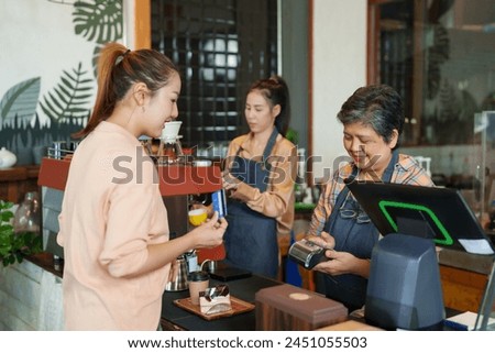 Businessman shop owner elderly Asian retired pensioner employee cafe small business smiling holding card machine The customer holding credit card to pay cash register The daughter making coffee 