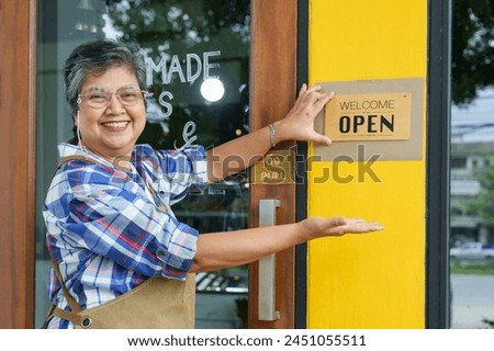 Asian Elderly Smiling women,  Welcoming senior business. placing an open sign, inviting patrons into the family cafe. happiness of opening coffee shop in morning small family business
