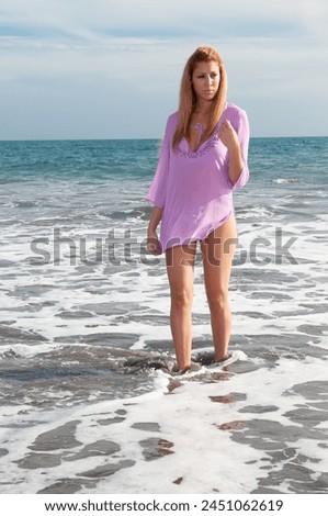 beautiful woman with long hair and pink eyes, in pink dress, on the beach in summer