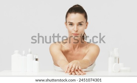 Gorgeous middle aged woman touching her perfect skin. Beautiful portrait of a 40-50 year old woman advertising anti-aging facial products, salon care, skin tightening, isolated on white background. Royalty-Free Stock Photo #2451074301
