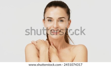 Gorgeous middle aged woman touching her perfect skin. Beautiful portrait of a 40-50 year old woman advertising anti-aging facial products, salon care, skin tightening, isolated on white background. Royalty-Free Stock Photo #2451074317