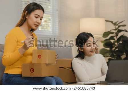 Two business owners are checking customer information on a package before it is delivered to the buyer, Two co-workers are checking that order data matches sales figures. Royalty-Free Stock Photo #2451085743