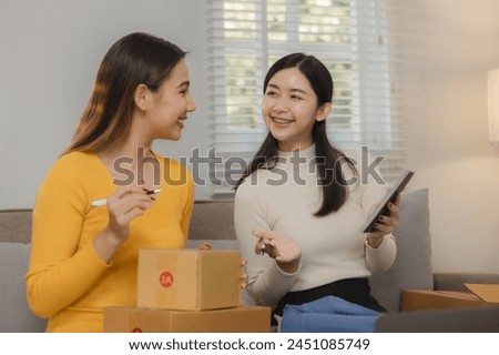 Two business owners are checking customer information on a package before it is delivered to the buyer, Two co-workers are checking that order data matches sales figures. Royalty-Free Stock Photo #2451085749