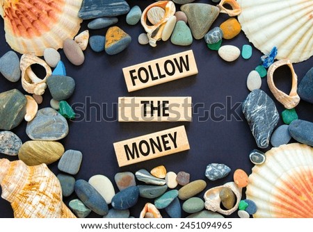 Follow the money symbol. Concept words Follow the money on beautiful wooden blocks. Beautiful black table black background. Sea shell stone. Business and follow the money concept. Copy space.